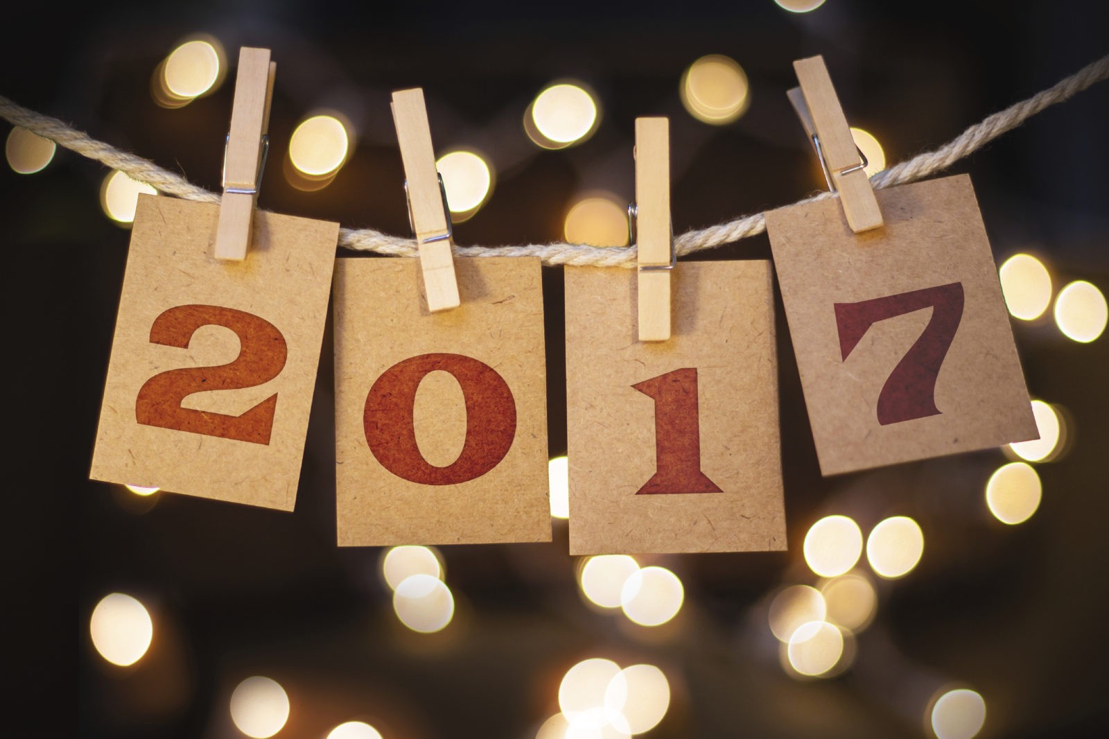 The word 2017 spelled out on clothespin clipped cards in front of glowing lights.